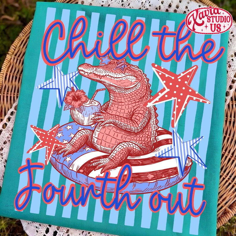 May include: A teal and blue Fourth of July themed decorative towel. The towel features a cartoon alligator wearing star-shaped sunglasses, relaxing on a red, white, and blue inner tube, and holding a coconut drink. The text "Chill the Fourth out" is written on the towel.
