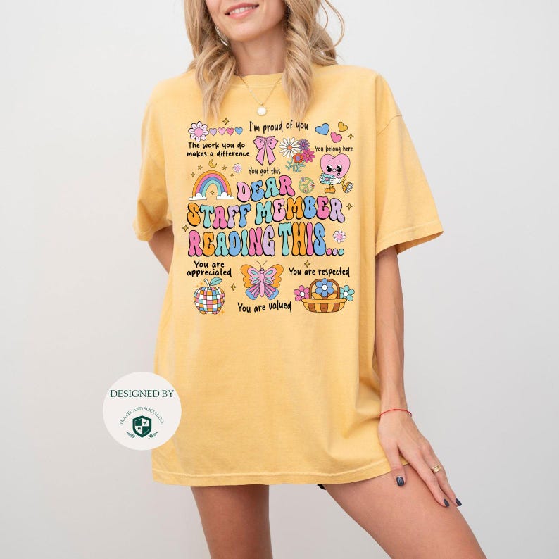 May include: A yellow t-shirt with a colorful graphic design that says "Dear Staff Member Reading This... You are appreciated. You are respected. You are valued." The graphic includes a rainbow, a butterfly, a flower, and a basket.