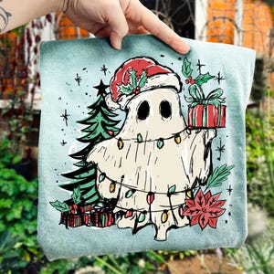 May include: A light blue Christmas-themed graphic featuring a cartoon ghost wearing a Santa hat and holding a wrapped gift. The ghost is decorated with Christmas lights and surrounded by a Christmas tree, poinsettia, and other festive elements.