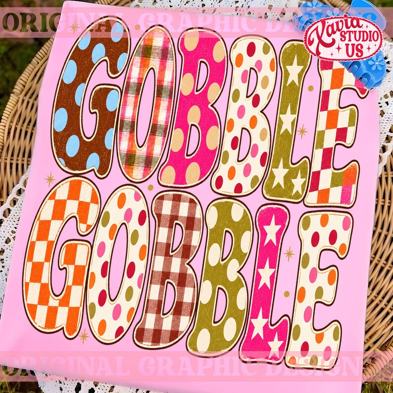 May include: A light pink t-shirt featuring the text GOBBLE GOBBLE in large, bold letters. Each letter displays a unique pattern, including polka dots, plaid, checkered prints, and stars in various colors like brown, orange, pink, and olive green.