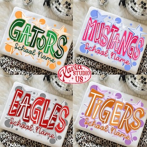 May include: Four white t-shirts with school names in bold, colorful fonts. The shirts feature the names "GATORS", "MUSTANGS", "EAGLES", and "TIGERS", each with a unique design and star accents. The shirts are displayed on a leopard print surface.