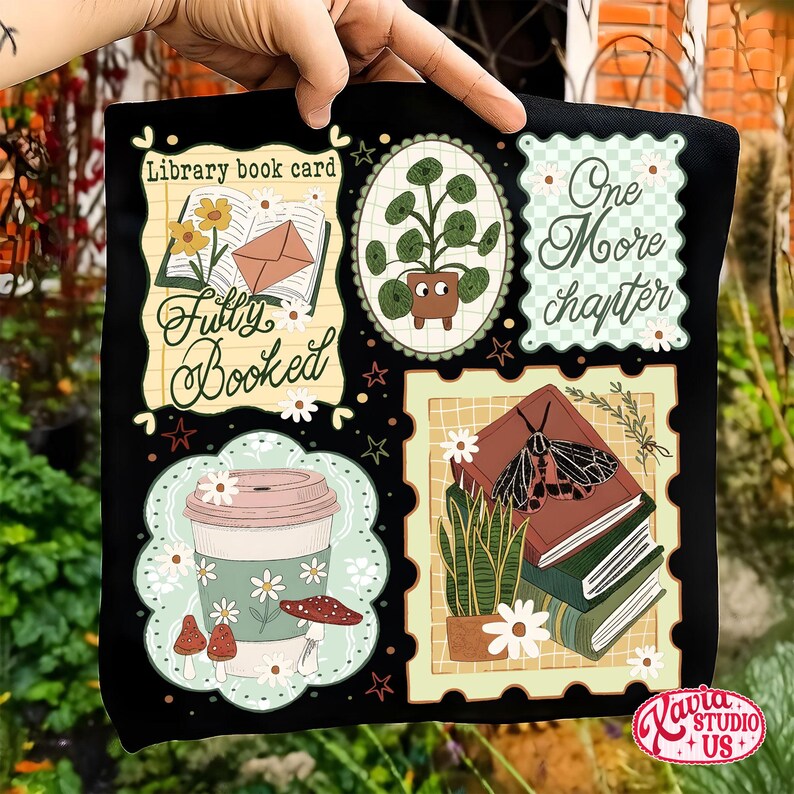 May include: Black tote bag featuring book-themed illustrations. Designs include a coffee cup, potted plant, and stacks of books with a moth. Text includes "Fully Booked" and "One More Chapter". The bag has a floral and botanical theme.