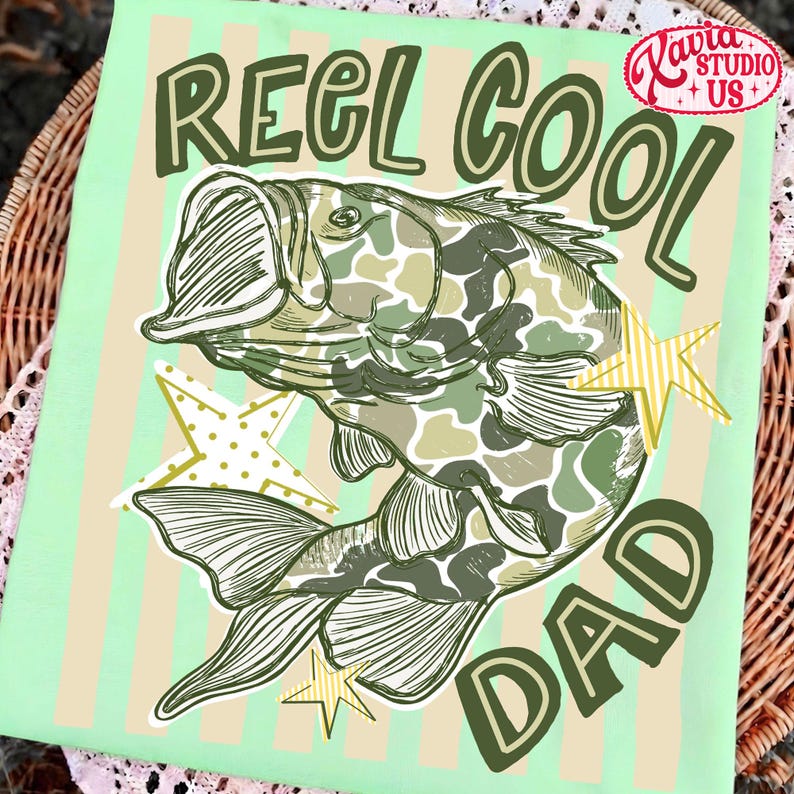 May include: A light green graphic featuring a fish with camouflage pattern, the words "REEL COOL DAD", and star accents. The design is on a light green background with vertical stripes.