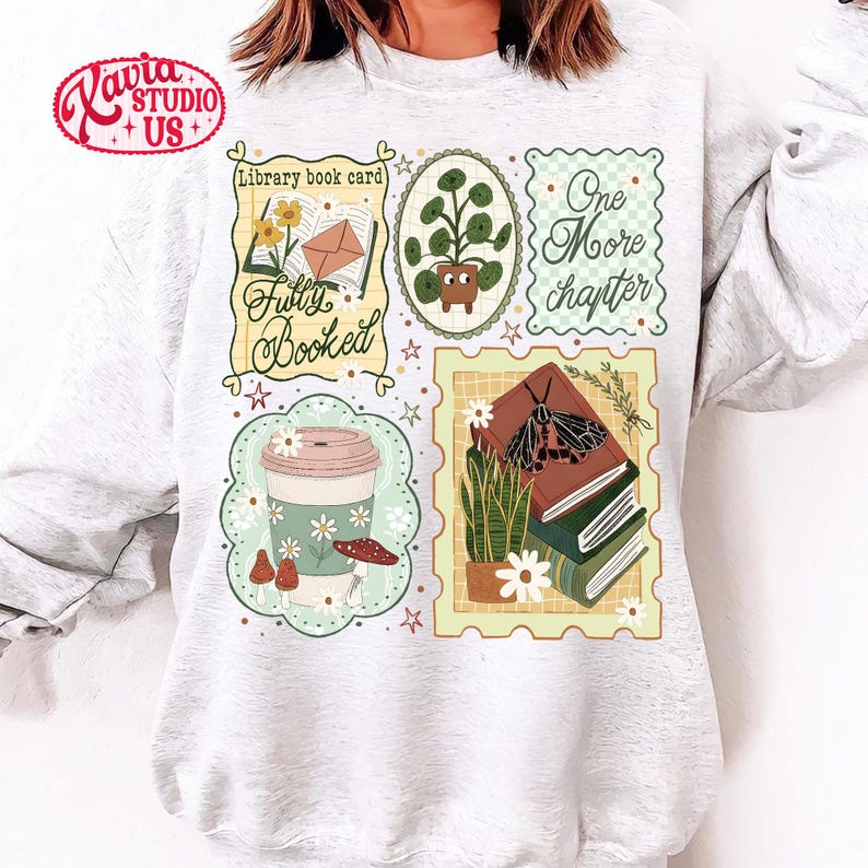 May include: A light gray sweatshirt featuring several illustrated patches with a book theme. Patches include a coffee cup, potted plant, books, and the phrases "Library book card", "Fully Booked", and "One More Chapter".
