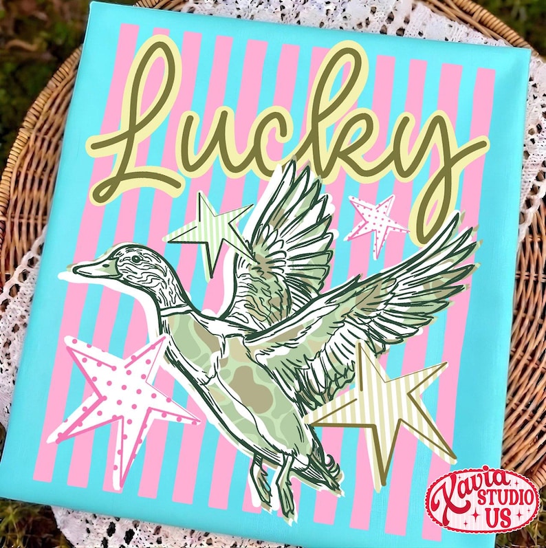 May include: A canvas print with a duck illustration and the word "Lucky" in a script font. The background is light blue with pink and white vertical stripes. The duck is green and white with star accents.