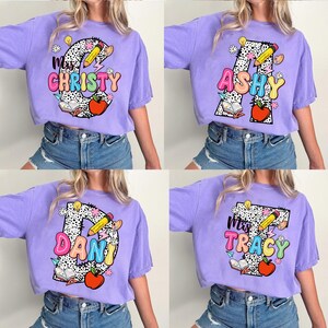 May include: Four purple t-shirts with a large letter and the word "Miss" in front of it. Each shirt has a different letter and name: "C", "Christy", "A", "Ashy", "D", "Dani", "T", "Tracy". Each letter is decorated with colorful school supplies and a polka dot pattern.