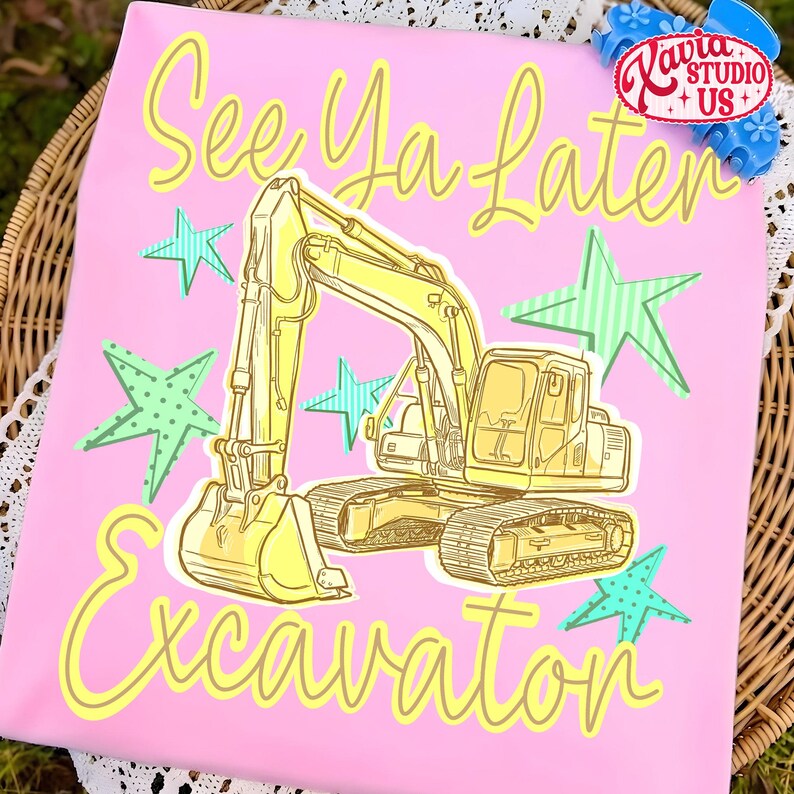 Pu&ograve; includere: T-shirt rosa con un'illustrazione di escavatore giallo e la scritta "See Ya Later Excavator" in un carattere giocoso. Il design include accenti di stelle verdi e blu, creando un look divertente e stravagante. La maglietta ha un contorno giallo chiaro.