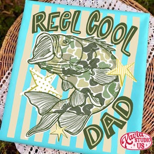 May include: Canvas art with a blue background and vertical beige stripes. The artwork features a fish with a camouflage pattern and the words "REEL COOL DAD" in green. Yellow star accents are also included.