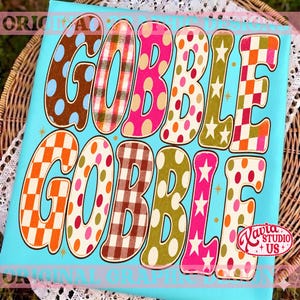 May include: A rectangular sign with a bright turquoise background featuring the text GOBBLE GOBBLE in large, stylized letters. Each letter displays a unique pattern including polka dots, plaid, checkered squares, and stars in various colors.