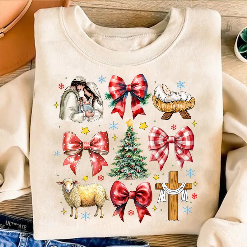 May include: Cream-colored sweatshirt featuring a Christmas-themed design. The design includes illustrations of a nativity scene, bows, a Christmas tree, a lamb, a baby in a manger, and a cross. The bows are red and white checkered. The sweatshirt is a festive holiday garment.