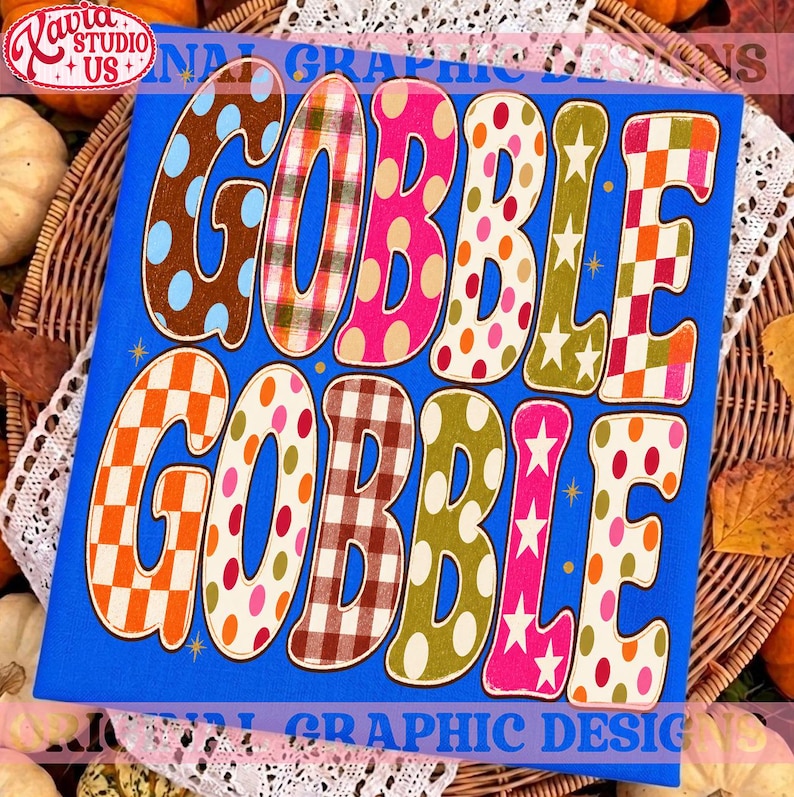 May include: A bright blue rectangular sign featuring the text GOBBLE GOBBLE in large, bold, bubble-style letters. Each letter displays a unique pattern, including polka dots, plaid, checkered squares, and stars in orange, pink, brown, and green.