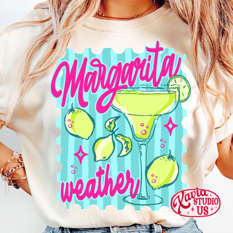 May include: A cream-coloured t-shirt with a bright graphic. It shows a margarita cocktail, lemons, and the words "Margarita weather" in pink. The design is set against a light blue background with a postage stamp border.