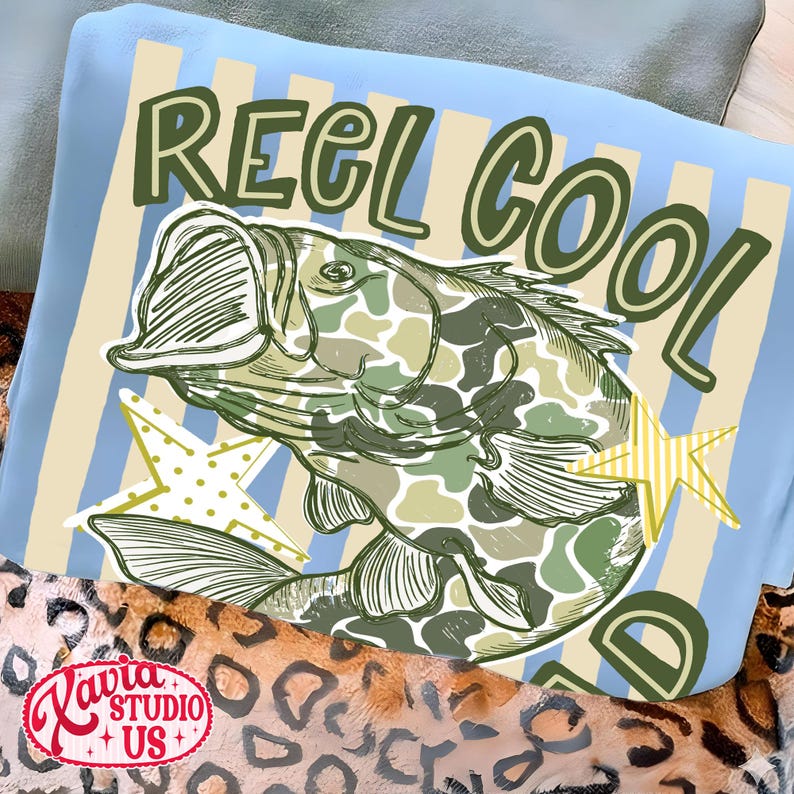 May include: A light blue pillow with the words "REEL COOL" in green lettering. A fish with a camouflage pattern is in the center, with two yellow star accents. The pillow is on a leopard print blanket.
