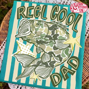 May include: A teal and cream striped decorative towel with the words "REEL COOL DAD" and a fish illustration in green camouflage. The towel also features star accents and the "Xavia Studio + US" logo.