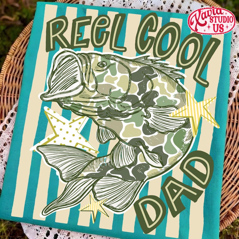 May include: A teal and cream striped decorative towel with the words "REEL COOL DAD" and a fish illustration in green camouflage. The towel also features star accents and the "Xavia Studio + US" logo.