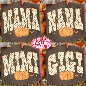 May include: A dark brown t-shirt featuring four variations of a graphic design with the words MAMA, NANA, MIMI, and GIGI. Each word is printed in a large, cream-colored, polka-dot font with a pumpkin and small orange bats underneath.