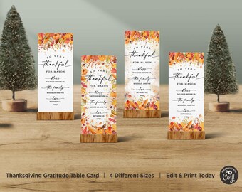 Puede incluir: Cuatro tarjetas de mesa de Acción de Gracias imprimibles con un diseño de follaje otoñal. Las tarjetas presentan el texto "So Very Thankful for [Name]" con un lugar para completar un nombre. Las tarjetas también incluyen el texto "Bless the food before us, the family beside us, and the love between us. Amen."