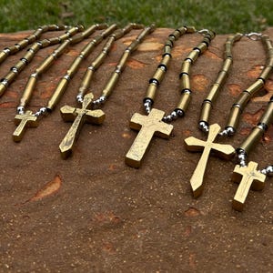 May include: Five gold cross necklaces with bullet casings and silver beads. The crosses are different sizes and have a worn, antique look.