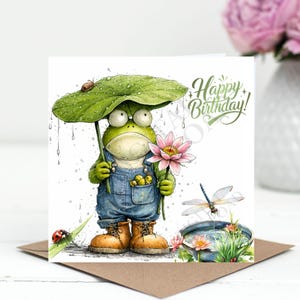 May include: A birthday card with a cartoon frog in dungarees, sheltering under a leaf and holding a lotus flower. The card reads "Happy Birthday!" and features a dragonfly, ladybug, and water lily in a pond.