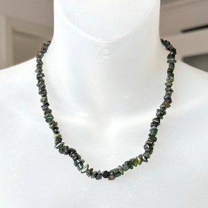 May include: A necklace made of dark green and black gemstone chips. The necklace is on a white mannequin.