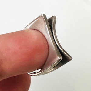 May include: A silver ring with a geometric design. The ring is made of two overlapping squares.