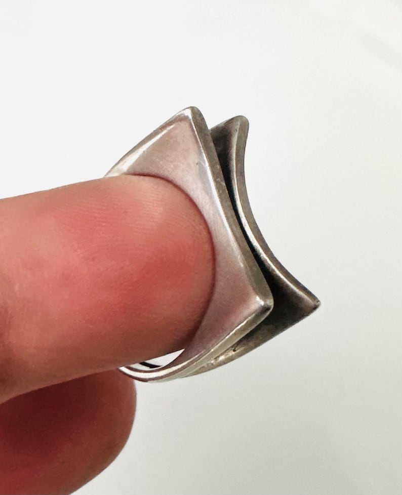 May include: A silver ring with a geometric design. The ring is made of two overlapping squares.