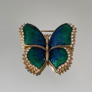 May include: A gold-tone butterfly brooch with green and blue enamel and clear rhinestones around the edges.