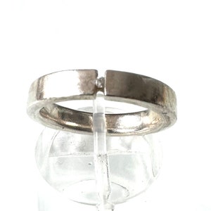 May include: A silver ring with a simple design. The ring is open on one side and has a small gap in the band.