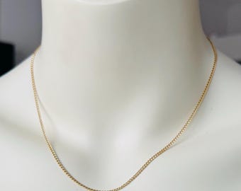 May include: A gold chain necklace on a white mannequin.