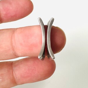May include: A silver ring with two curved bands that are joined together.