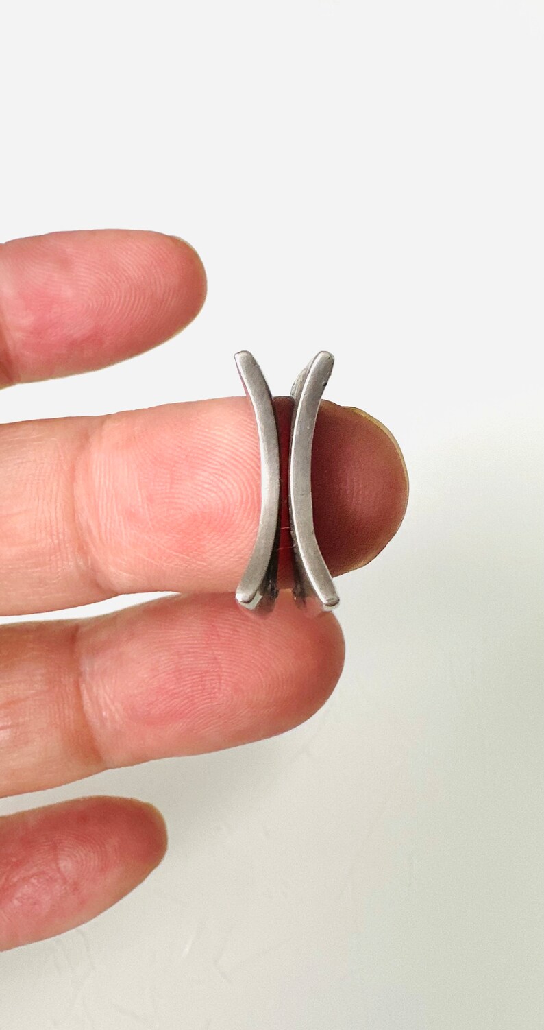 May include: A silver ring with two curved bands that are joined together.