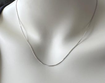 May include: A silver chain necklace on a white mannequin.
