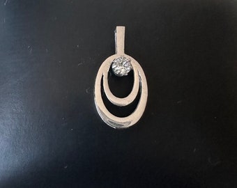 May include: A silver pendant with a single clear stone set in a double oval design.