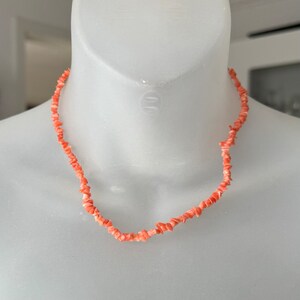 May include: A necklace made of small, irregular pieces of coral. The coral is a light pink color.