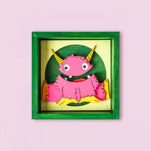 Hölzernes Porträt des niedlichen rosafarbenen Monsters, glückliches lustiges Babymonster, wunderliche Kinderzimmerdekoration, Zeichentrickmonstercharakter im Rahmen