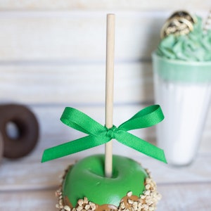 May include: A green apple dipped in caramel and topped with chopped nuts, tied with a green ribbon and attached to a wooden stick.