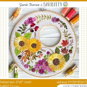 May include: A hand embroidery pattern for a harvest wreath featuring sunflowers, fall leaves, and purple flowers. The pattern is 12 inches by 12 inches and is designed for intermediate skill levels. The pattern is called "Harvest Wreath Stitch" and is by Sarah Thomas of Sariditty.