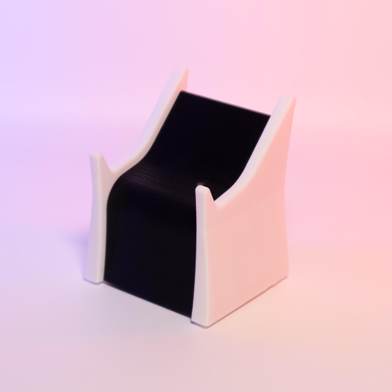 以下が含まれることがあります： モダンなジュエリーディスプレイスタンド。 黒いベルベットの曲面が、白い縁取りのある淡いピンク色の2つのサポートの間に挟まれています。 背景はピンクと紫のグラデーションです。