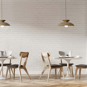 May include: Interior of a restaurant with round white tables, wooden chairs, and pendant lights. The chairs have wooden backs and dark grey seats. The background is a white brick wall. The tables are approximately 75 cm in diameter.