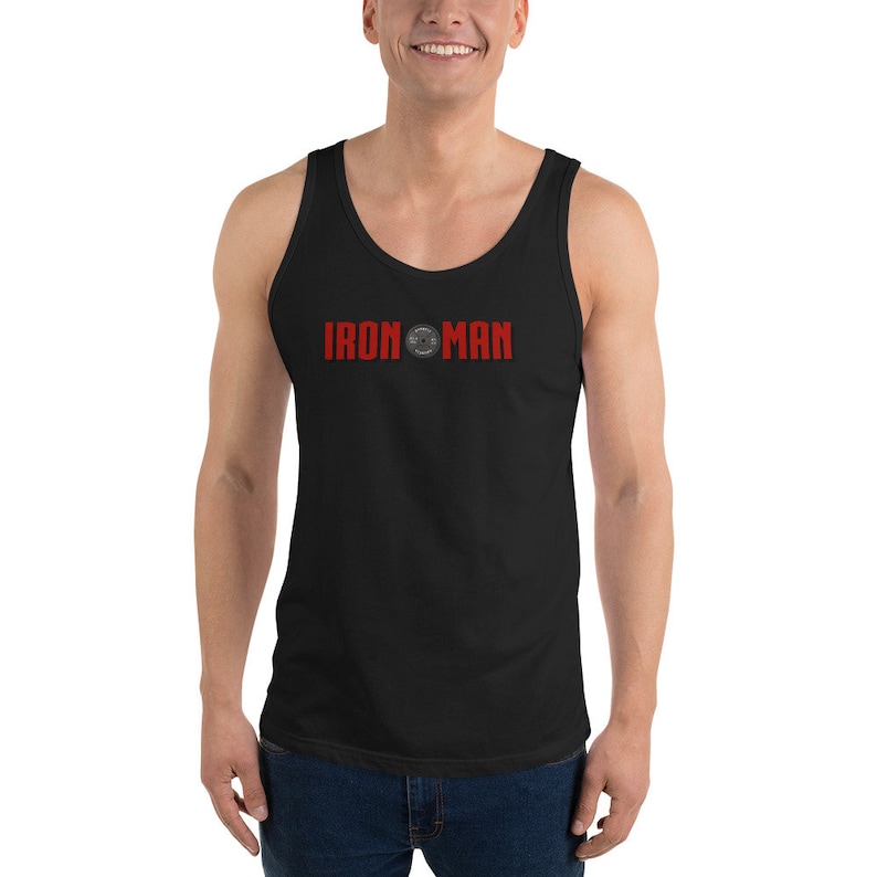 May include: Black tank top with the red text "IRON MAN" across the chest. The text is above a circular graphic. The tank top is sleeveless and made of a soft material.