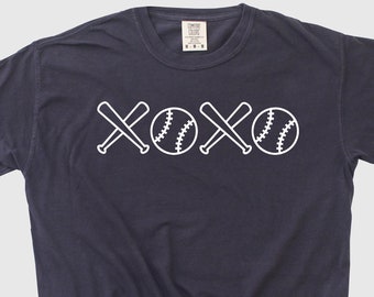 May include: A dark blue t-shirt with a white graphic design of baseball bats and balls forming the word "XOXO".