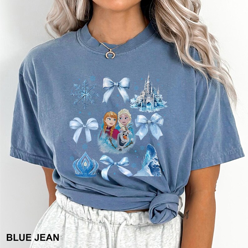 May include: A blue jean colored t-shirt featuring a graphic of characters from the movie Frozen, snowflakes, bows, and a castle. The text "BLUE JEAN" is printed at the bottom of the shirt.