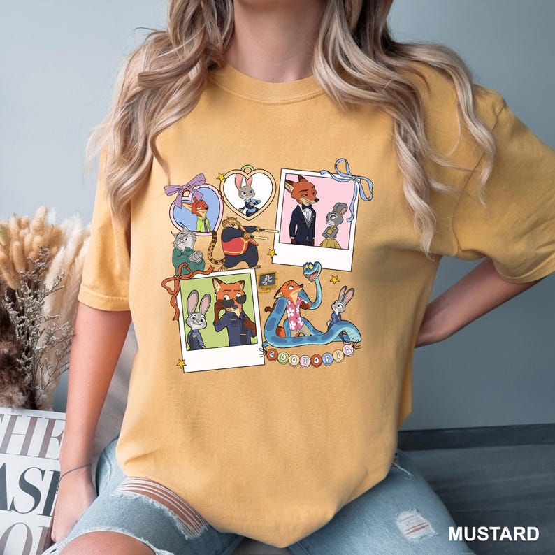 May include: Mustard-coloured t-shirt featuring a collage of cartoon characters from Zootropolis. The design includes framed images of the characters, with the word "Zootopia" at the bottom. The shirt is made of a soft material.