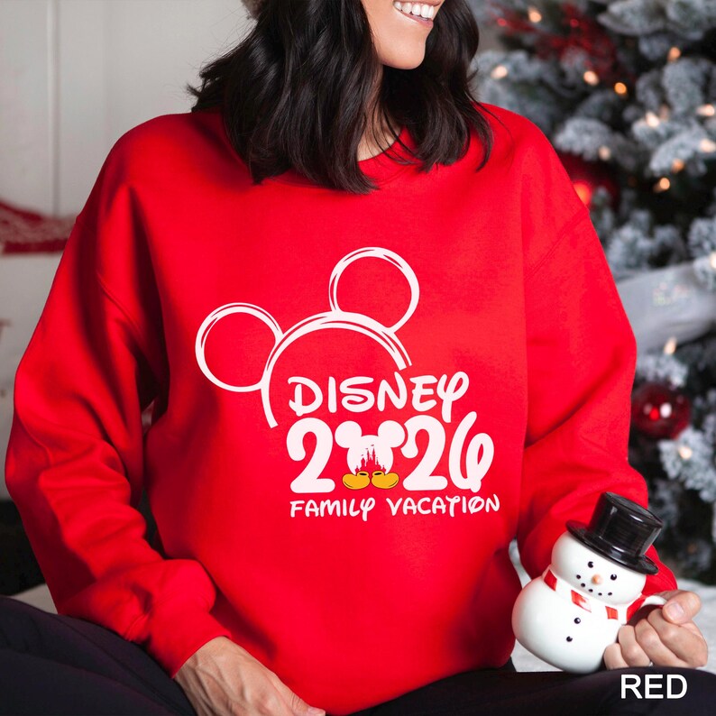 以下が含まれることがあります： 白いミッキーマウスのデザインと「DISNEY 2026 FAMILY VACATION」の文字が入った赤いスウェットシャツ。家族旅行にぴったりのアイテムです。