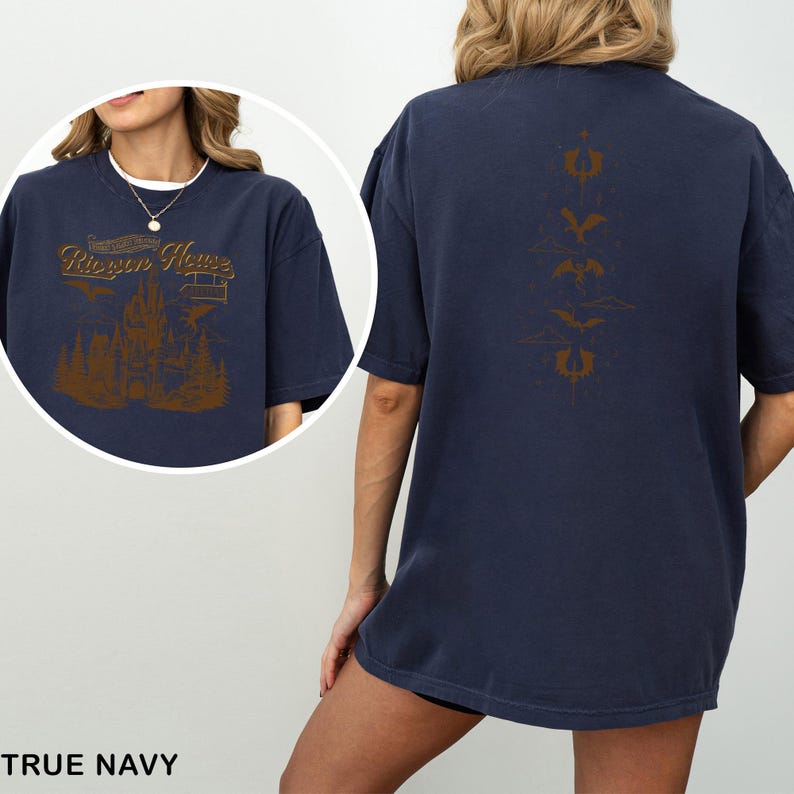 May include: True navy blue t-shirt with a brown graphic on the front featuring text "Riepen House" above a castle and trees. The back of the shirt has a vertical brown design of bats and other symbols. The shirt is a comfortable, oversized fit.