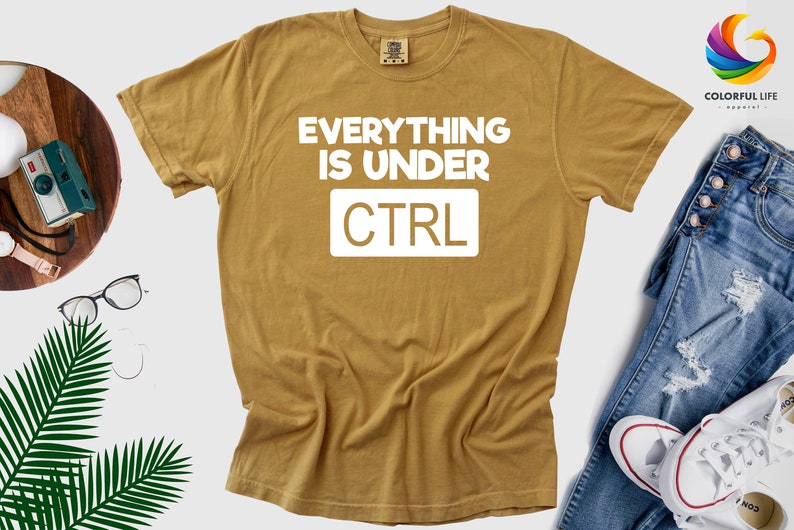 May include: A mustard yellow t-shirt with the text "EVERYTHING IS UNDER CTRL" in white.