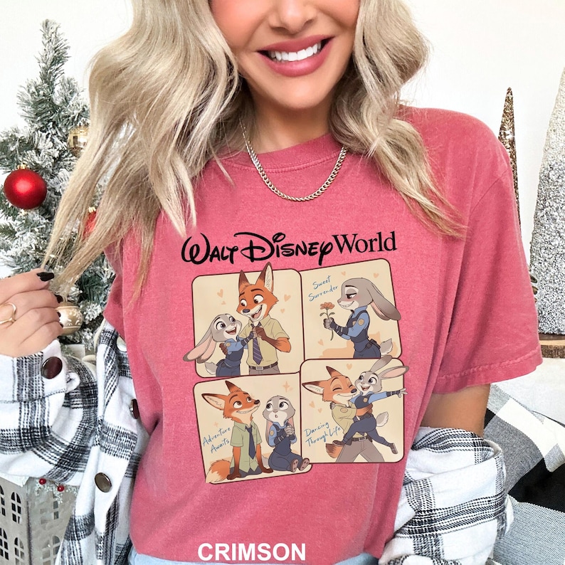 May include: Crimson-colored t-shirt featuring a cartoon graphic of characters from Zootopia. The shirt has the text "Walt Disney World" at the top and the word "Crimson" at the bottom. The graphic shows the characters in different poses.