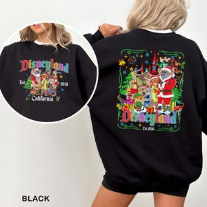 May include: Black sweatshirt with a colorful Disneyland graphic. The design features various Disney characters in festive attire, with the text "Disneyland Est. 2016 California". The sweatshirt has a crew neck and long sleeves.
