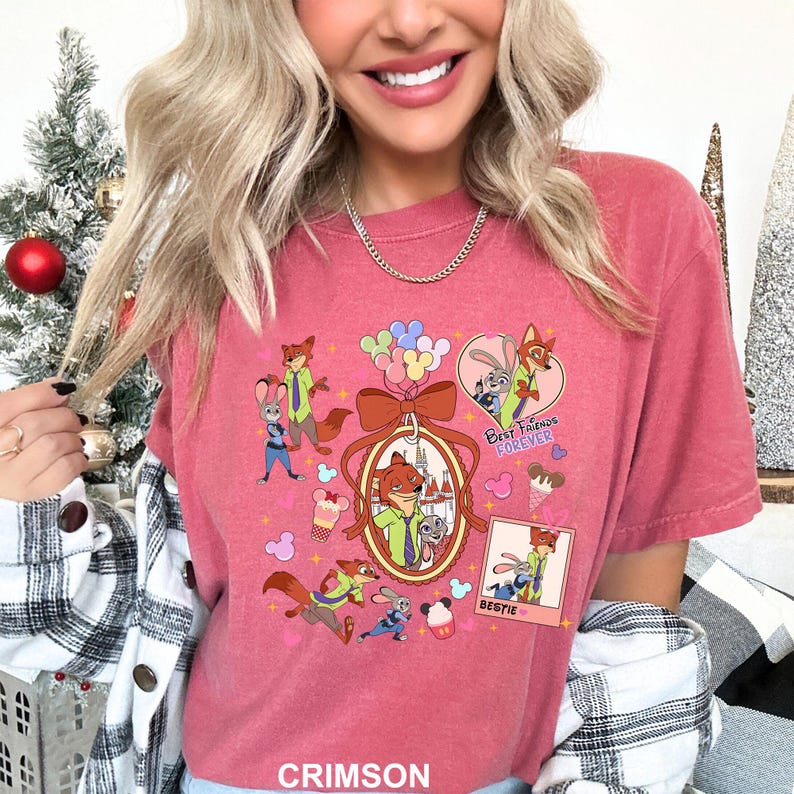 Op de afbeelding: Karmozijnrood T-shirt met stripfiguren. Het ontwerp bevat een vos en een konijn met de woorden "Best Friends Forever" en "Bestie". Andere afbeeldingen zijn ballonnen, ijs en een strik.