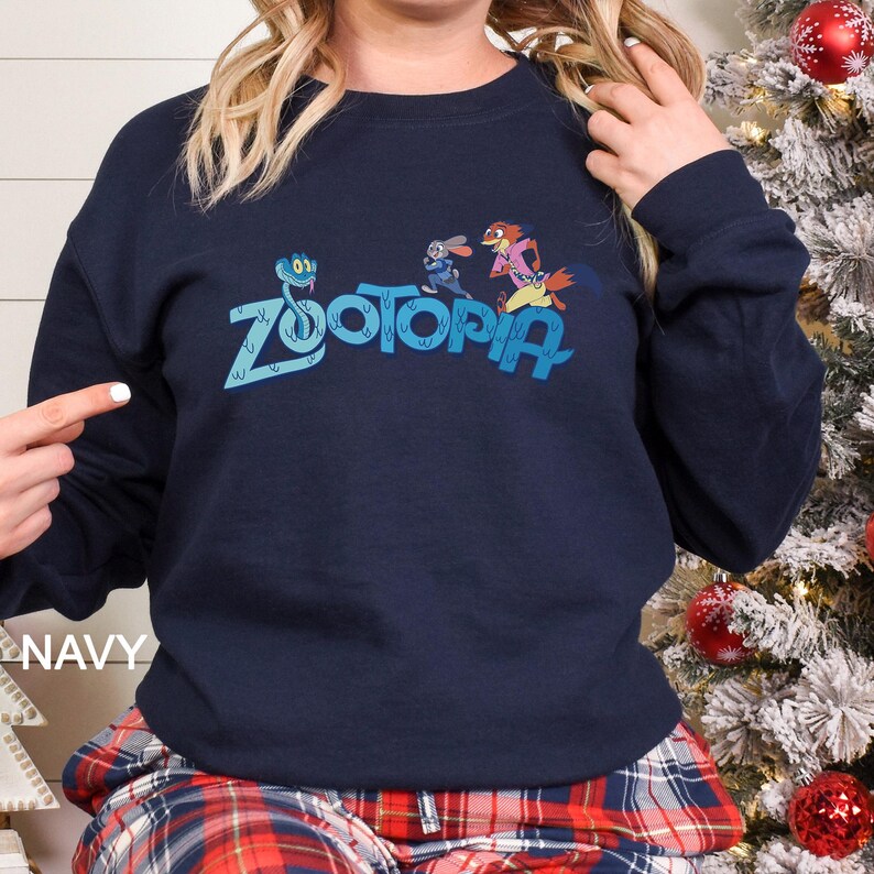 May include: Navy blue crew neck sweatshirt with the word "Zootopia" in light blue, and cartoon characters. The word "NAVY" is printed in white on the bottom left. The sweatshirt is a dark blue colour.